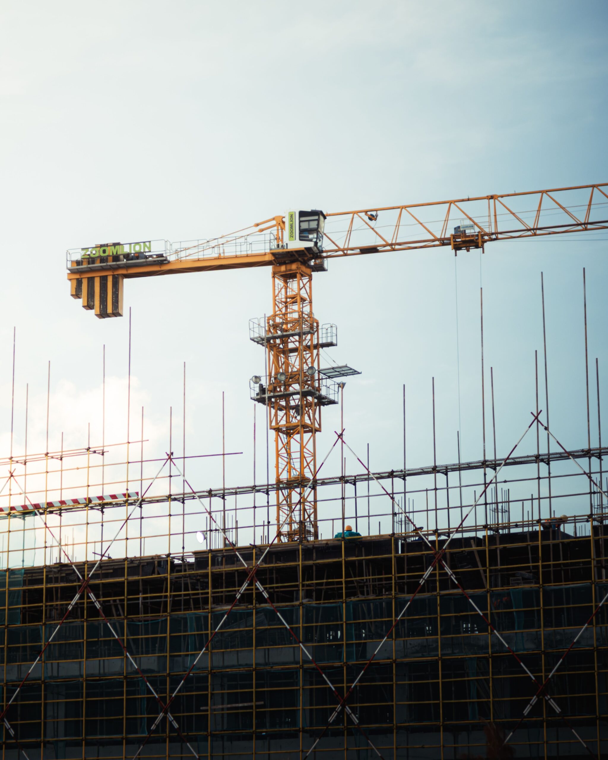 Obra nueva en construcción con grúas y estructura metálica al atardecer.